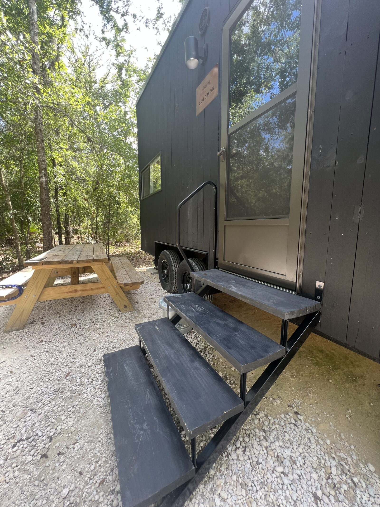 Maximizing Airbnb Investment Returns with Prefab Homes: A Guide to Boosting ROI 1 Multiple modern wood-clad tiny houses on wheels spaced out in a forest setting, similar to the Getaway house model.
