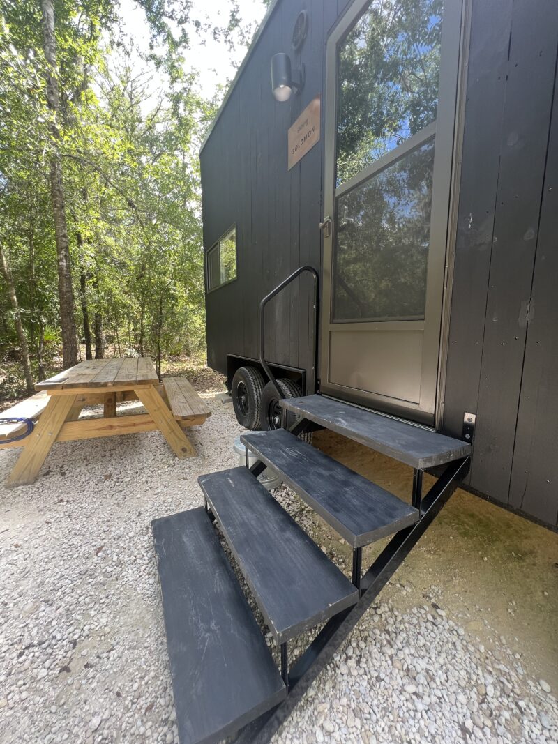 Multiple modern wood-clad tiny houses on wheels spaced out in a forest setting, similar to the Getaway house model.