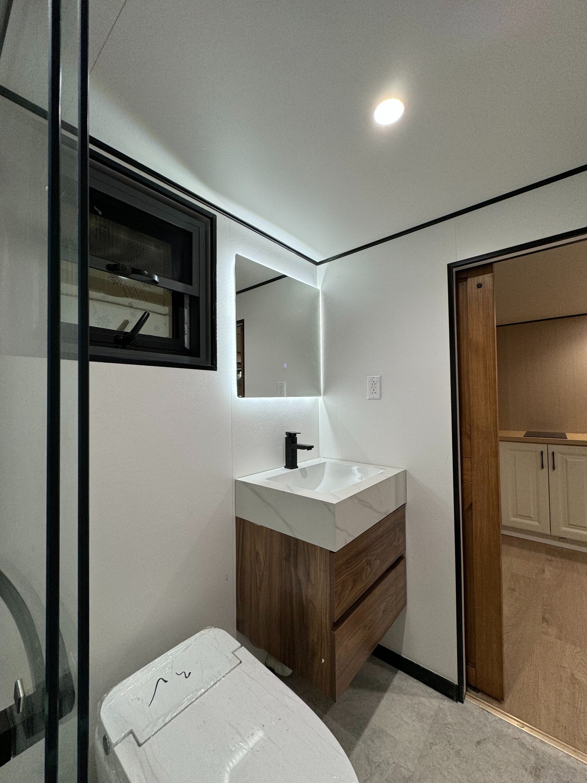 MagicSlide tiny house bedroom with a fold-down double bed beside floor-to-ceiling glass sliding doors