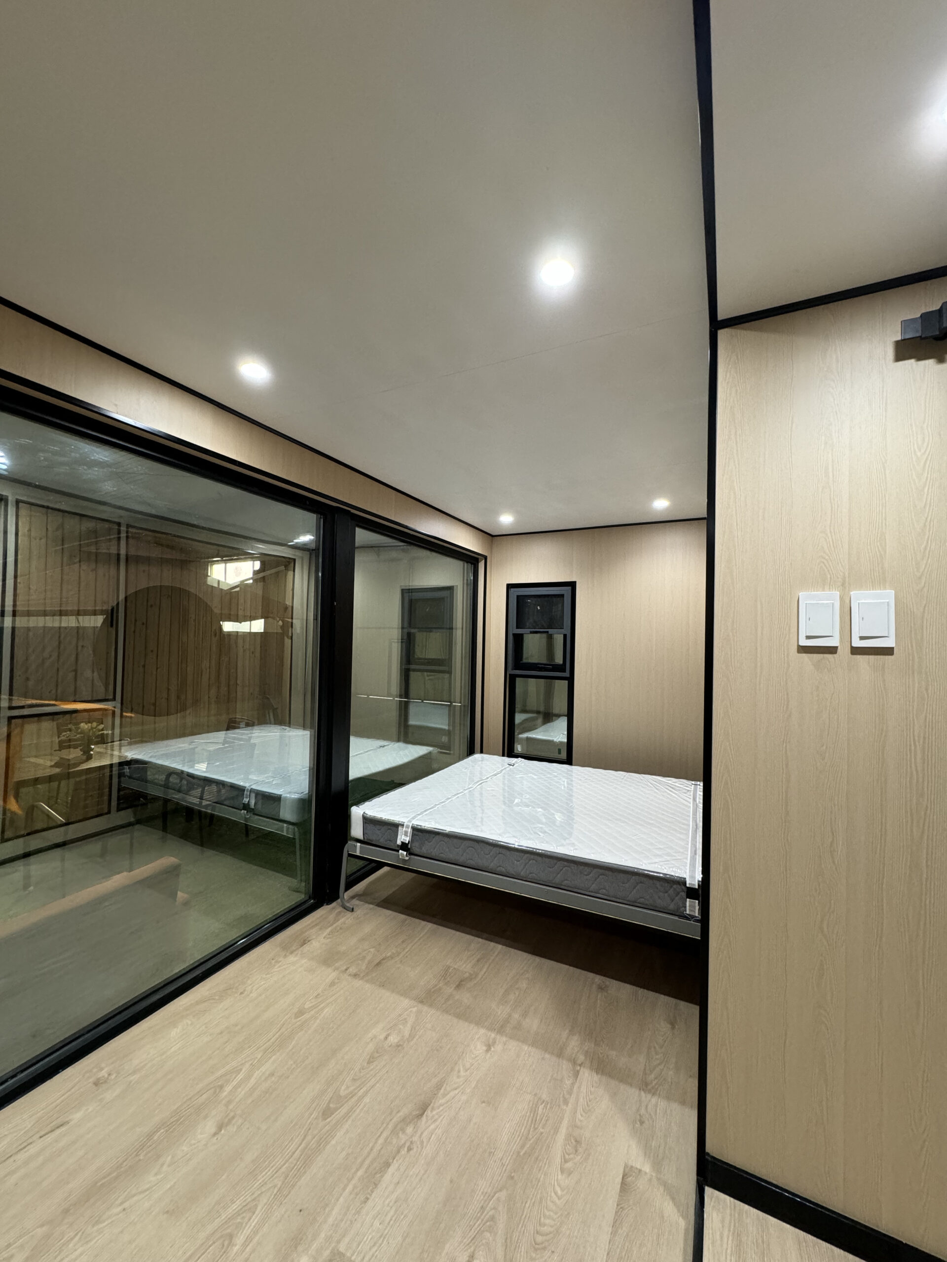 MagicSlide expandable tiny house interior showing Murphy bed and kitchen after sliding out to full 230 sqft