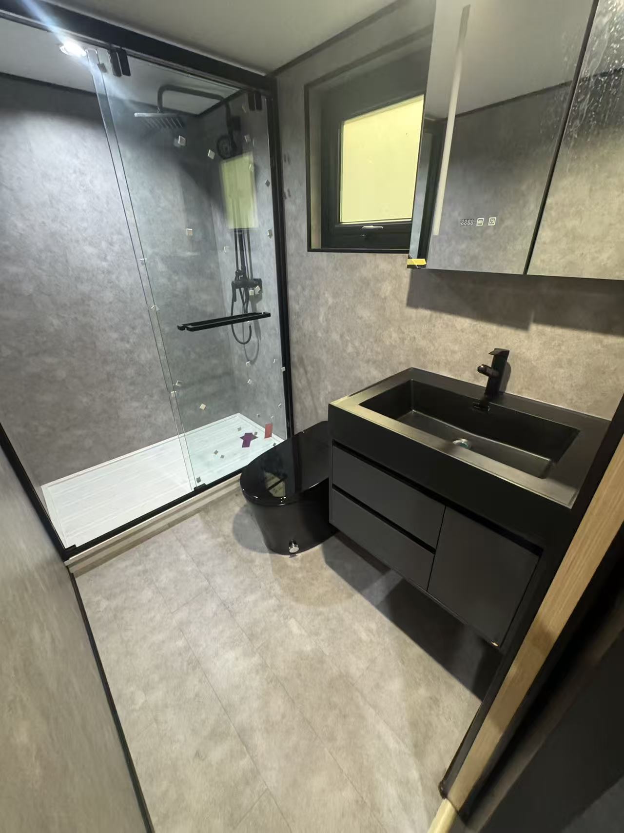 MagicSlide tiny house kitchen with gray cabinets, induction cooktop, window and fold-out dining table
